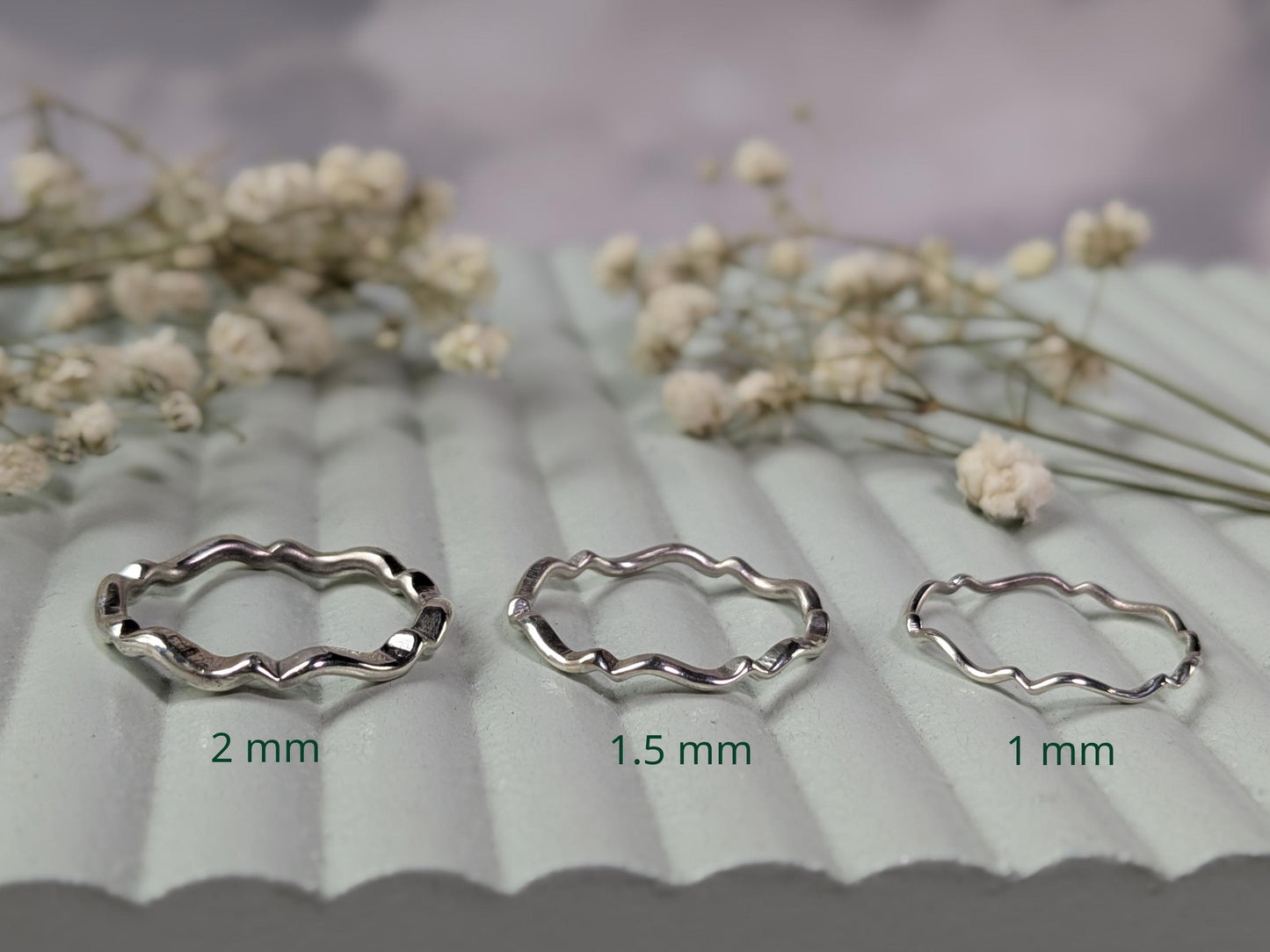A comparison of the same ring available in different thicknesses. The ring is sterling silver and has a scalloped wave pattern throughout the entire band. From left-to-right, the options available are: 2mm, 1.5mm, 1mm.