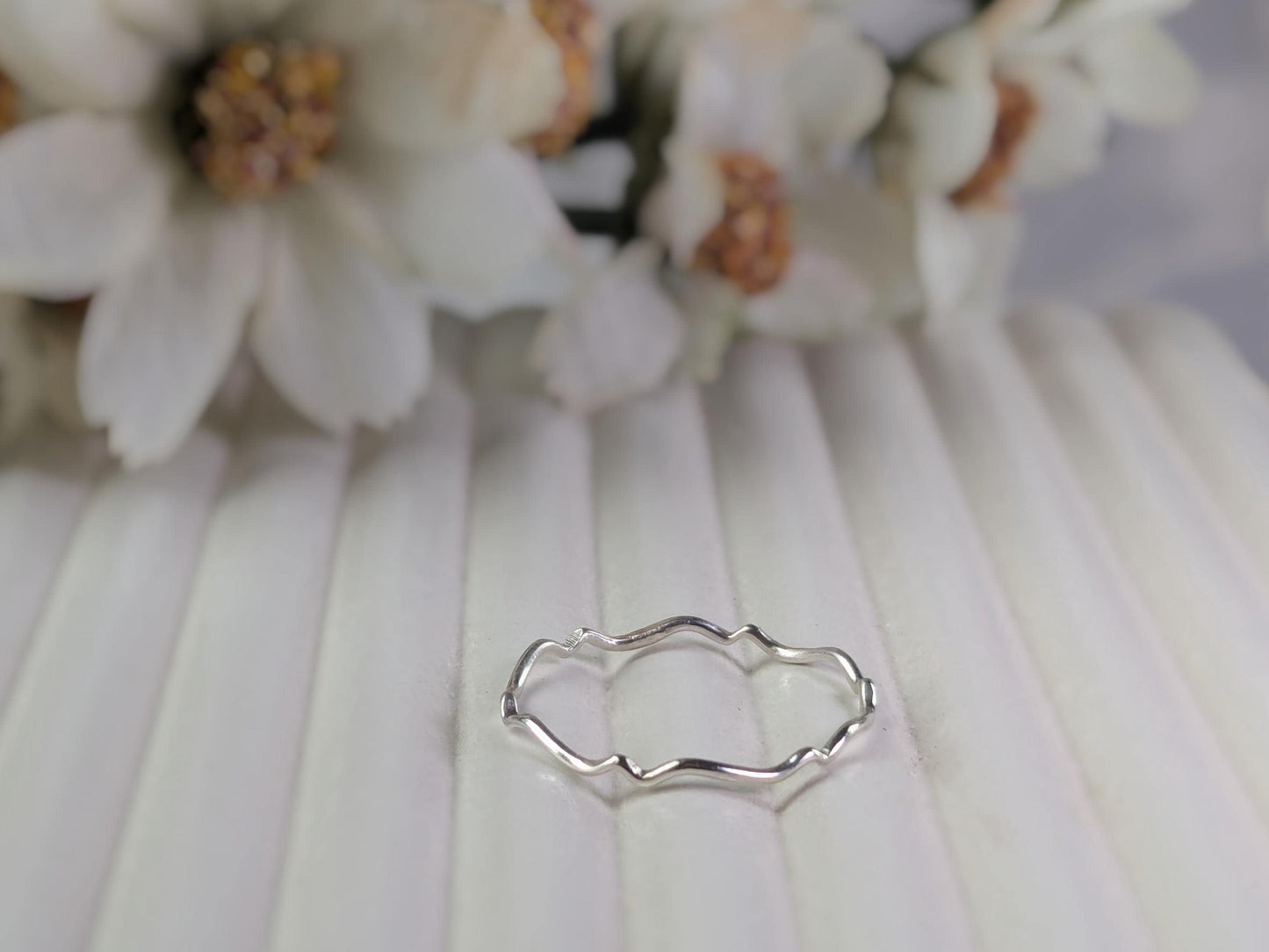 A delicate sterling silver ring with a scalloped wave pattern.
