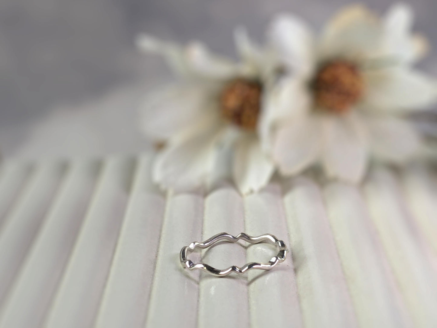 A simple sterling silver ring with a scalloped wave pattern.