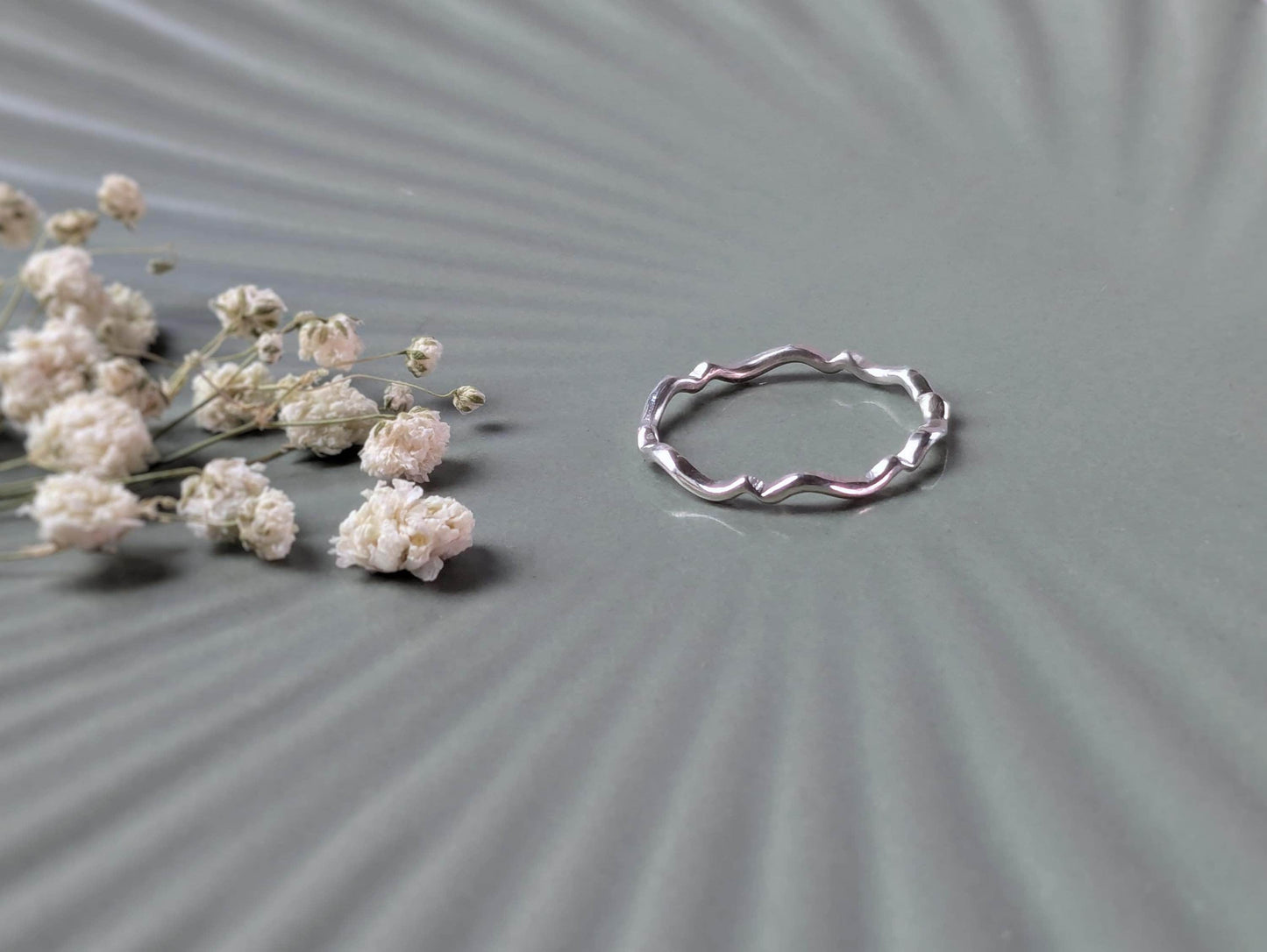 A simple sterling silver ring with a scalloped wave pattern.