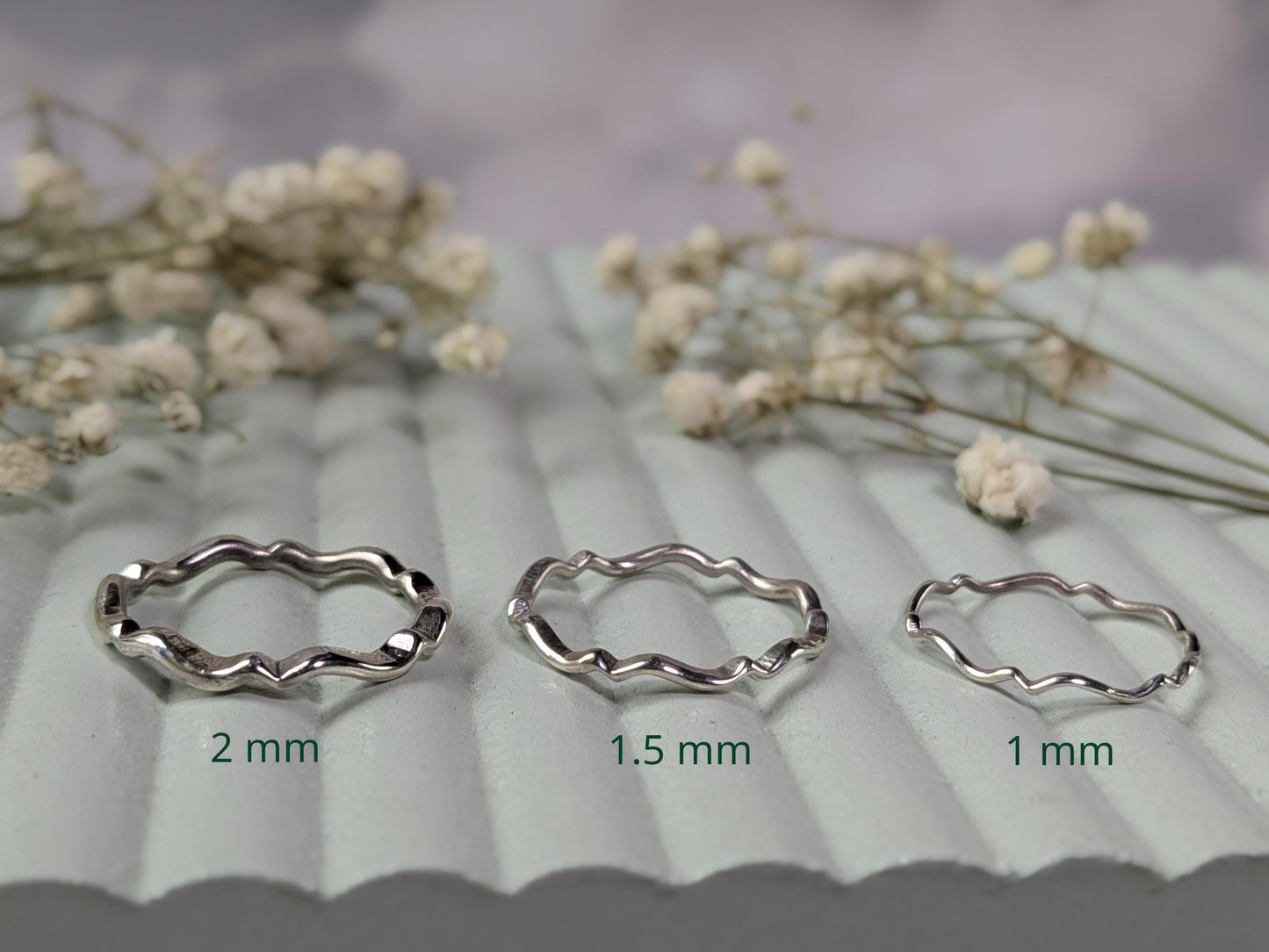 A comparison of the same ring available in different thicknesses. The ring is sterling silver and has a scalloped wave pattern throughout the entire band. From left-to-right, the options available are: 2mm, 1.5mm, 1mm.