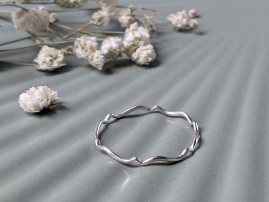 A delicate sterling silver ring with a scalloped wave pattern.