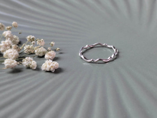 A simple sterling silver ring with a scalloped wave pattern.